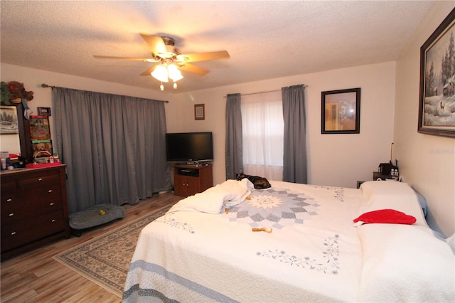 bedroom with a textured ceiling, wood-type flooring, and ceiling fan