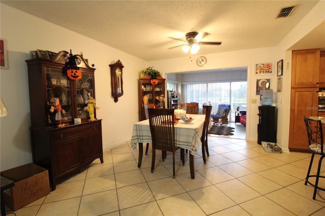 dining area with ceiling fan, light tile patterned floors, and a textured ceiling