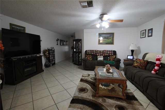 living room with ceiling fan, a textured ceiling, and light tile patterned flooring