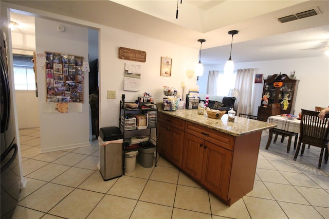 kitchen featuring light stone countertops, a wealth of natural light, hanging light fixtures, and light tile patterned floors