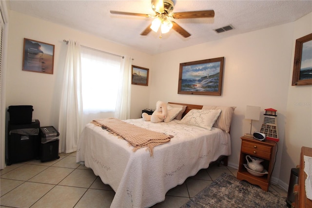 bedroom with ceiling fan, light tile patterned flooring, and a textured ceiling