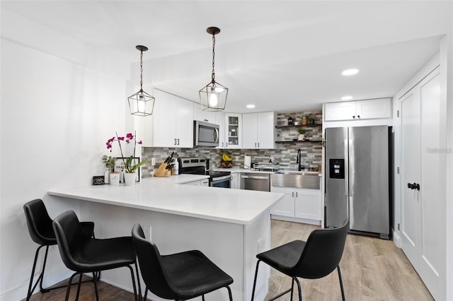 kitchen with appliances with stainless steel finishes, kitchen peninsula, sink, and white cabinets