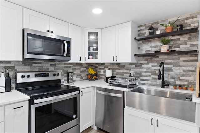 kitchen with appliances with stainless steel finishes, backsplash, sink, and white cabinetry