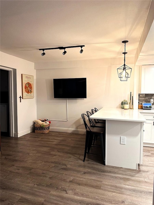 kitchen with white cabinets, a breakfast bar area, decorative light fixtures, and dark hardwood / wood-style flooring