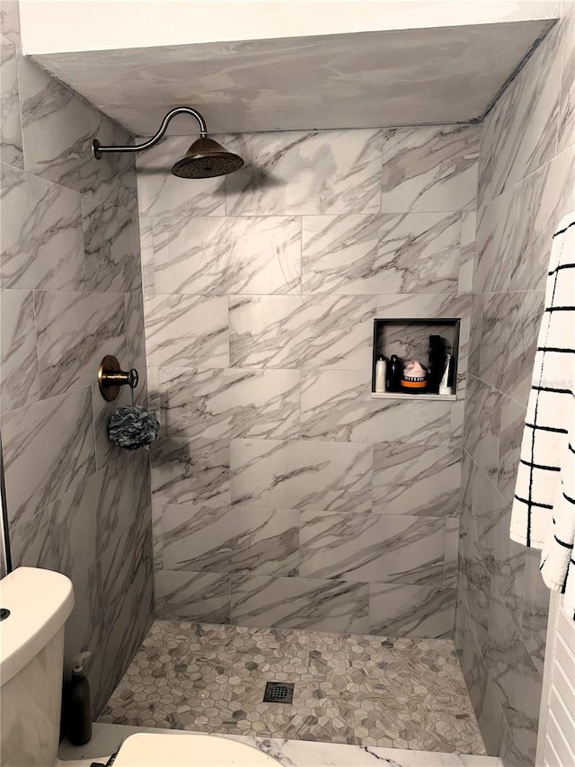 bathroom with a tile shower and toilet