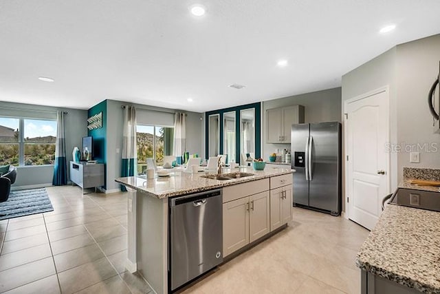 kitchen featuring gray cabinetry, stainless steel appliances, a kitchen island with sink, and sink