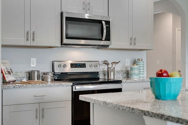 kitchen with light stone countertops, white cabinets, and appliances with stainless steel finishes