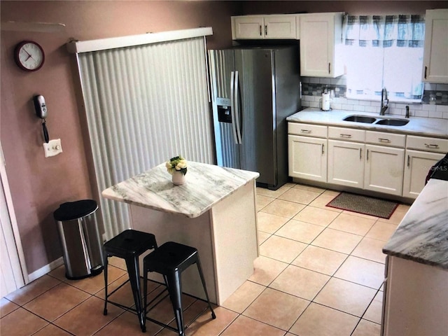 kitchen with white cabinetry, tasteful backsplash, light tile patterned floors, and stainless steel fridge