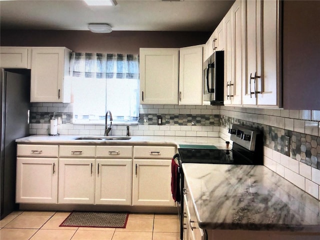 kitchen with sink, white cabinetry, stainless steel appliances, and light tile patterned floors