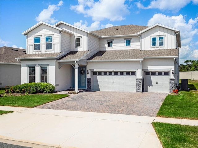 view of front of home featuring central air condition unit, a front yard, and a garage