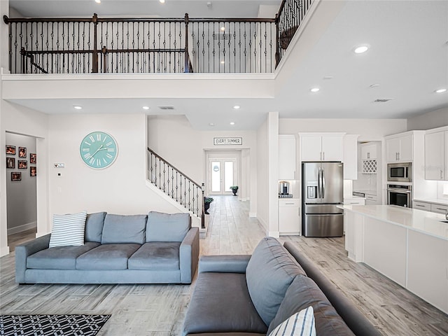 living room with light wood-type flooring and a high ceiling