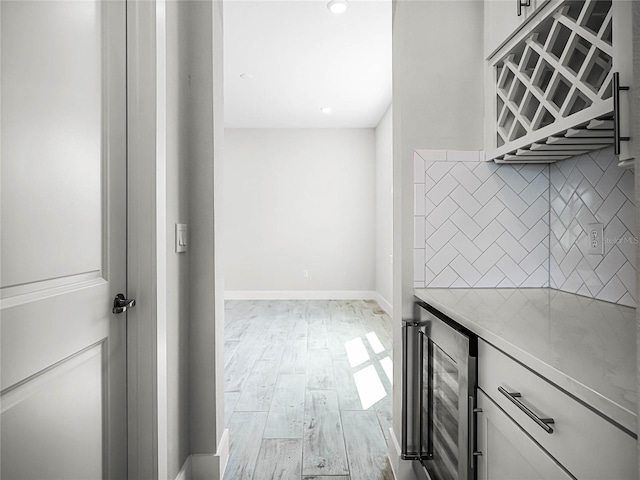 kitchen with backsplash, wine cooler, light hardwood / wood-style flooring, and white cabinets