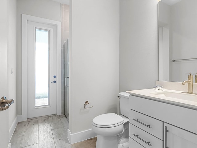 bathroom featuring a shower with door, vanity, wood-type flooring, and toilet