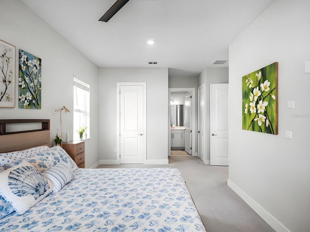 carpeted bedroom with ensuite bathroom and ceiling fan