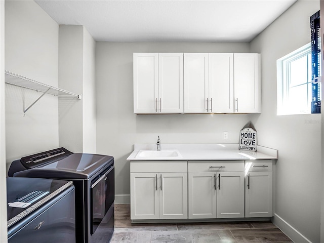 washroom with cabinets, separate washer and dryer, light hardwood / wood-style floors, and sink