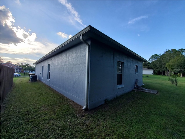 property exterior at dusk featuring a lawn