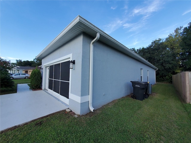 view of side of home featuring a lawn and a patio area