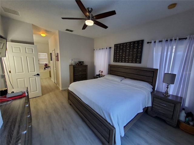 bedroom with ceiling fan, ensuite bathroom, and hardwood / wood-style floors