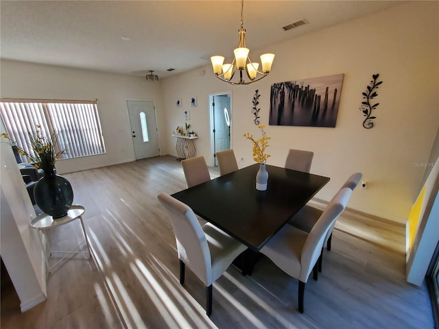 dining room with wood-type flooring and a notable chandelier