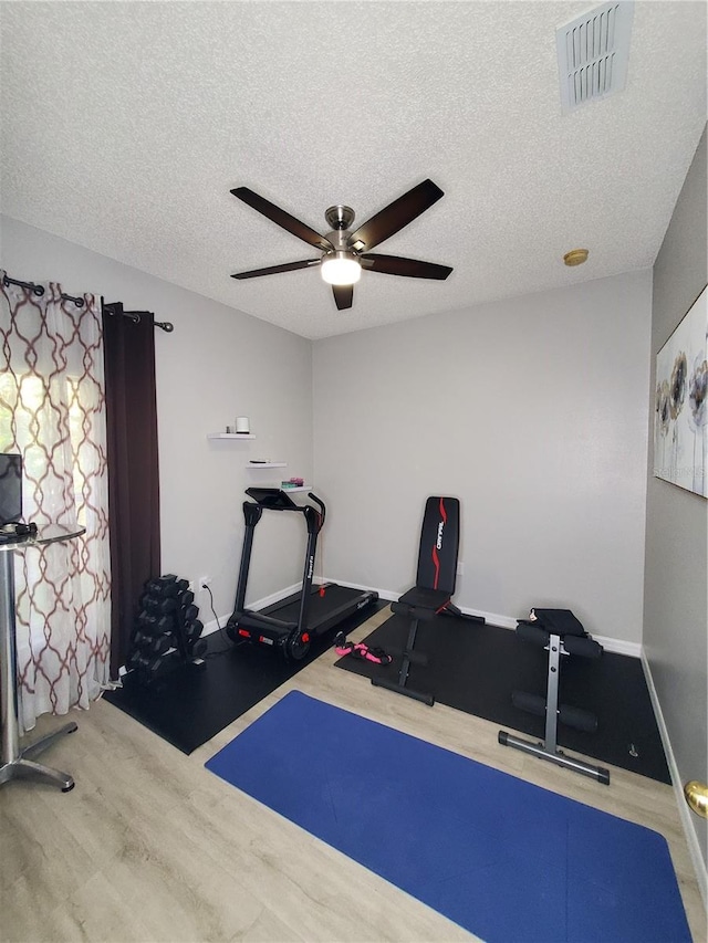 exercise area with wood-type flooring, a textured ceiling, and ceiling fan