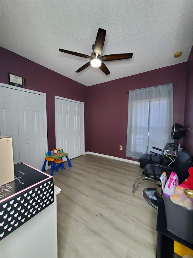 playroom featuring light hardwood / wood-style floors, ceiling fan, and a textured ceiling