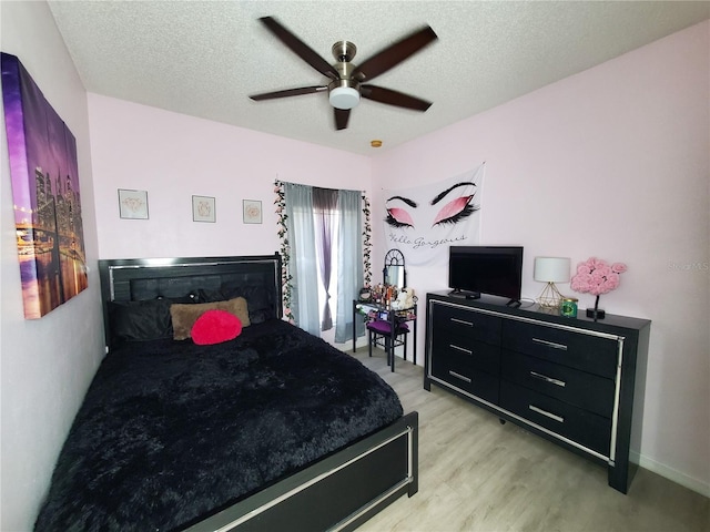 bedroom featuring light hardwood / wood-style flooring, ceiling fan, and a textured ceiling