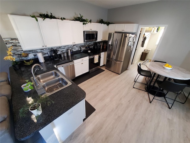 kitchen featuring stainless steel appliances, backsplash, sink, and white cabinetry