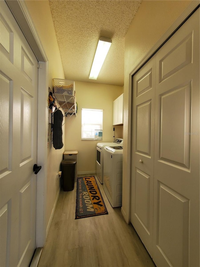 clothes washing area featuring cabinets, a textured ceiling, light hardwood / wood-style floors, and washing machine and dryer