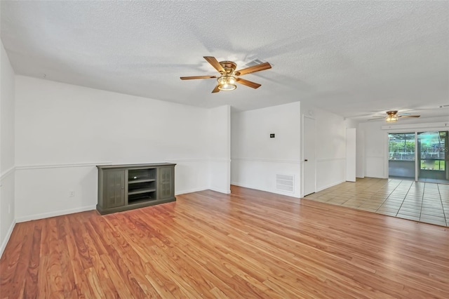 unfurnished living room with light hardwood / wood-style flooring, ceiling fan, and a textured ceiling