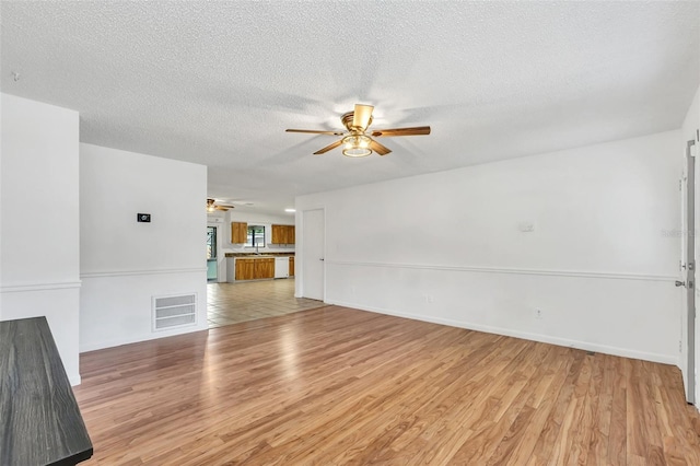 unfurnished living room featuring ceiling fan, a textured ceiling, and light hardwood / wood-style floors