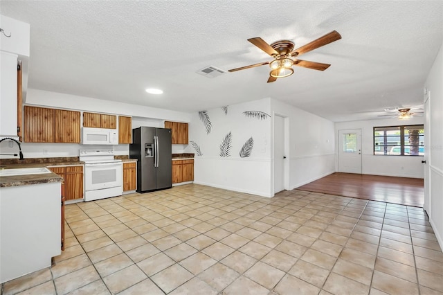 kitchen with ceiling fan, a textured ceiling, light tile patterned floors, and white appliances