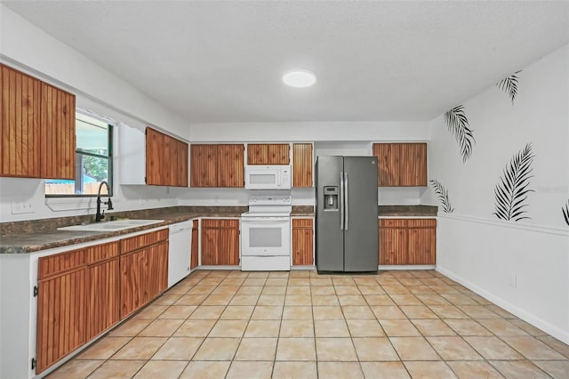 kitchen featuring a textured ceiling, white appliances, sink, and light tile patterned floors