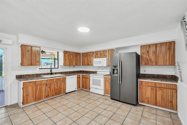 kitchen with light tile patterned floors, a textured ceiling, sink, and white appliances