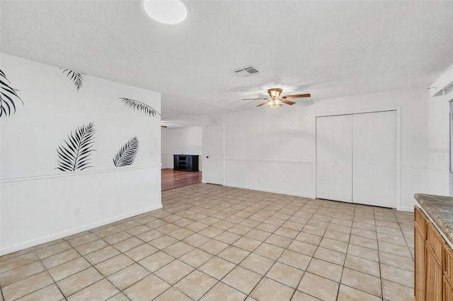 unfurnished living room featuring a textured ceiling, light tile patterned floors, and ceiling fan