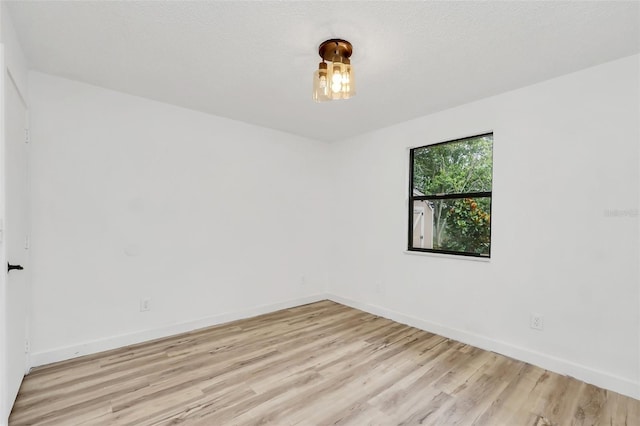 unfurnished room with a textured ceiling and light hardwood / wood-style floors