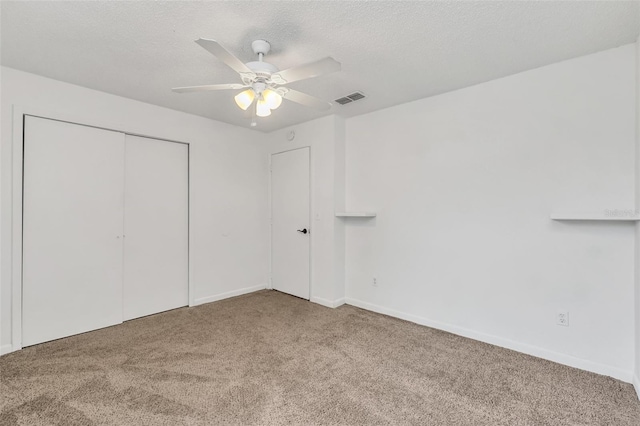 unfurnished bedroom with ceiling fan, carpet floors, a closet, and a textured ceiling