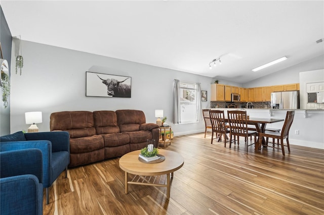 living room featuring lofted ceiling and light hardwood / wood-style flooring