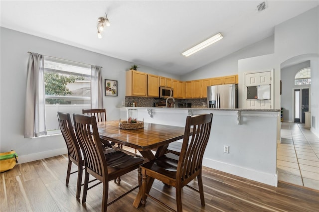 dining room featuring sink, vaulted ceiling, and hardwood / wood-style floors