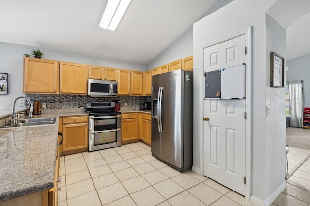 kitchen with appliances with stainless steel finishes, sink, vaulted ceiling, decorative backsplash, and light tile patterned floors