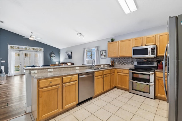 kitchen with appliances with stainless steel finishes, sink, kitchen peninsula, light hardwood / wood-style floors, and vaulted ceiling