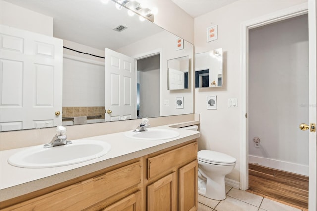 bathroom with toilet, vanity, and tile patterned floors