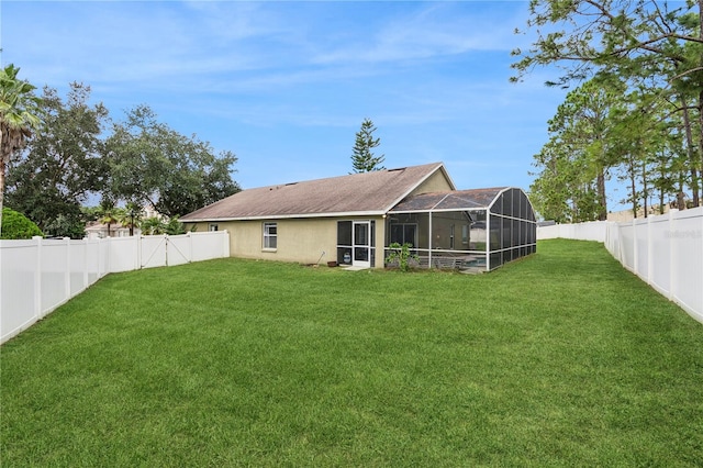 rear view of house with a lawn and a lanai