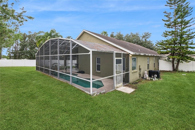 back of property with a yard, a patio, a fenced in pool, and glass enclosure