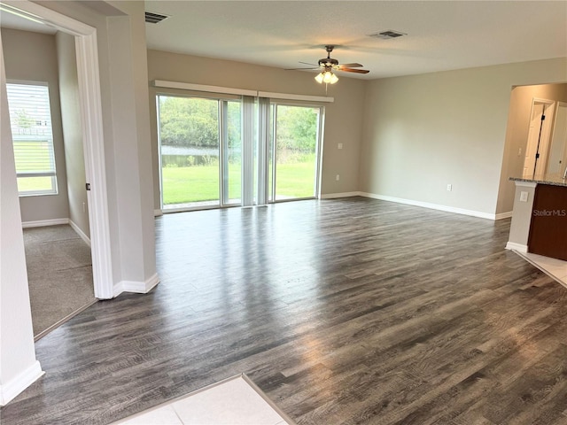 unfurnished living room featuring ceiling fan and dark wood-type flooring