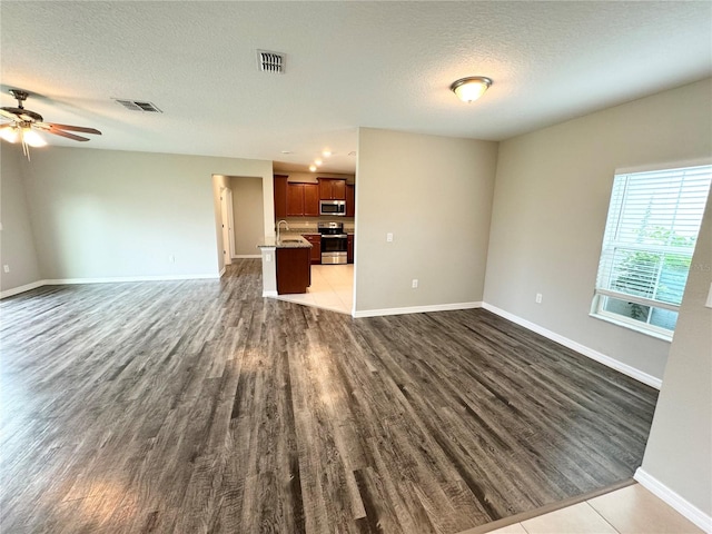 unfurnished living room with a textured ceiling, dark hardwood / wood-style flooring, ceiling fan, and sink