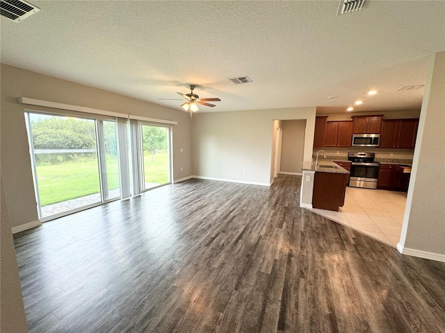 unfurnished living room with ceiling fan, sink, dark wood-type flooring, and a textured ceiling