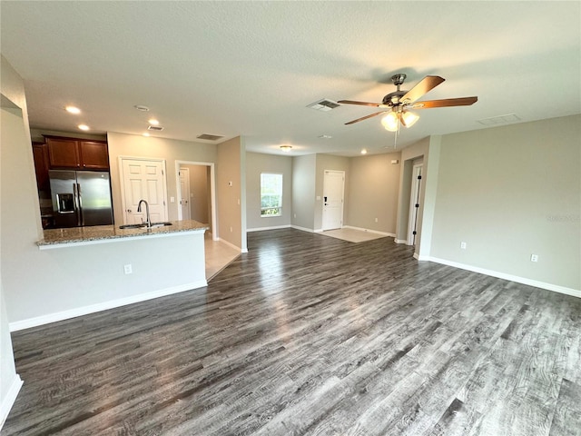 unfurnished living room with a textured ceiling, sink, dark wood-type flooring, and ceiling fan