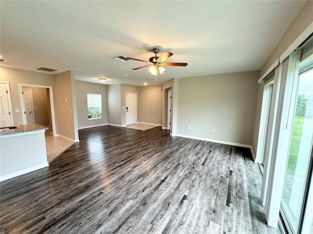 unfurnished living room with ceiling fan, a textured ceiling, and dark wood-type flooring