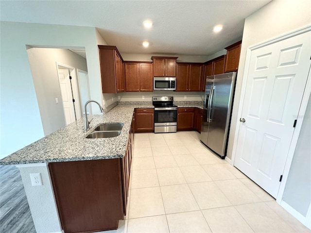 kitchen featuring light stone counters, appliances with stainless steel finishes, sink, and kitchen peninsula