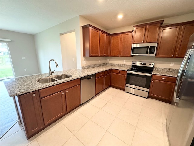 kitchen featuring appliances with stainless steel finishes, light stone countertops, kitchen peninsula, and sink